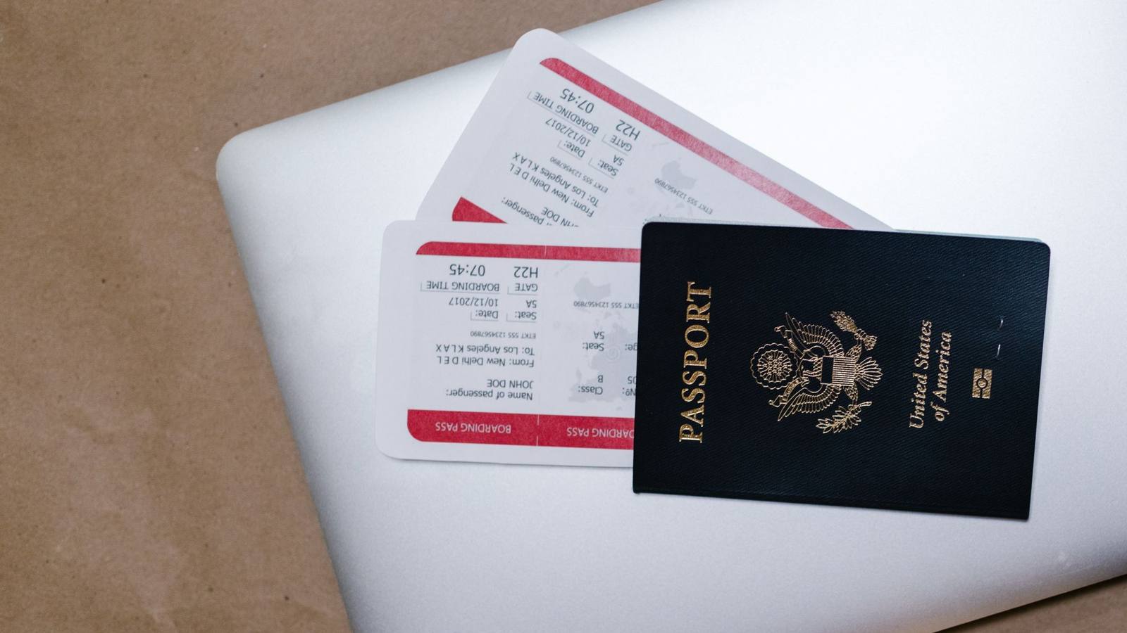 A passport and printed papers resting on top of a laptop.