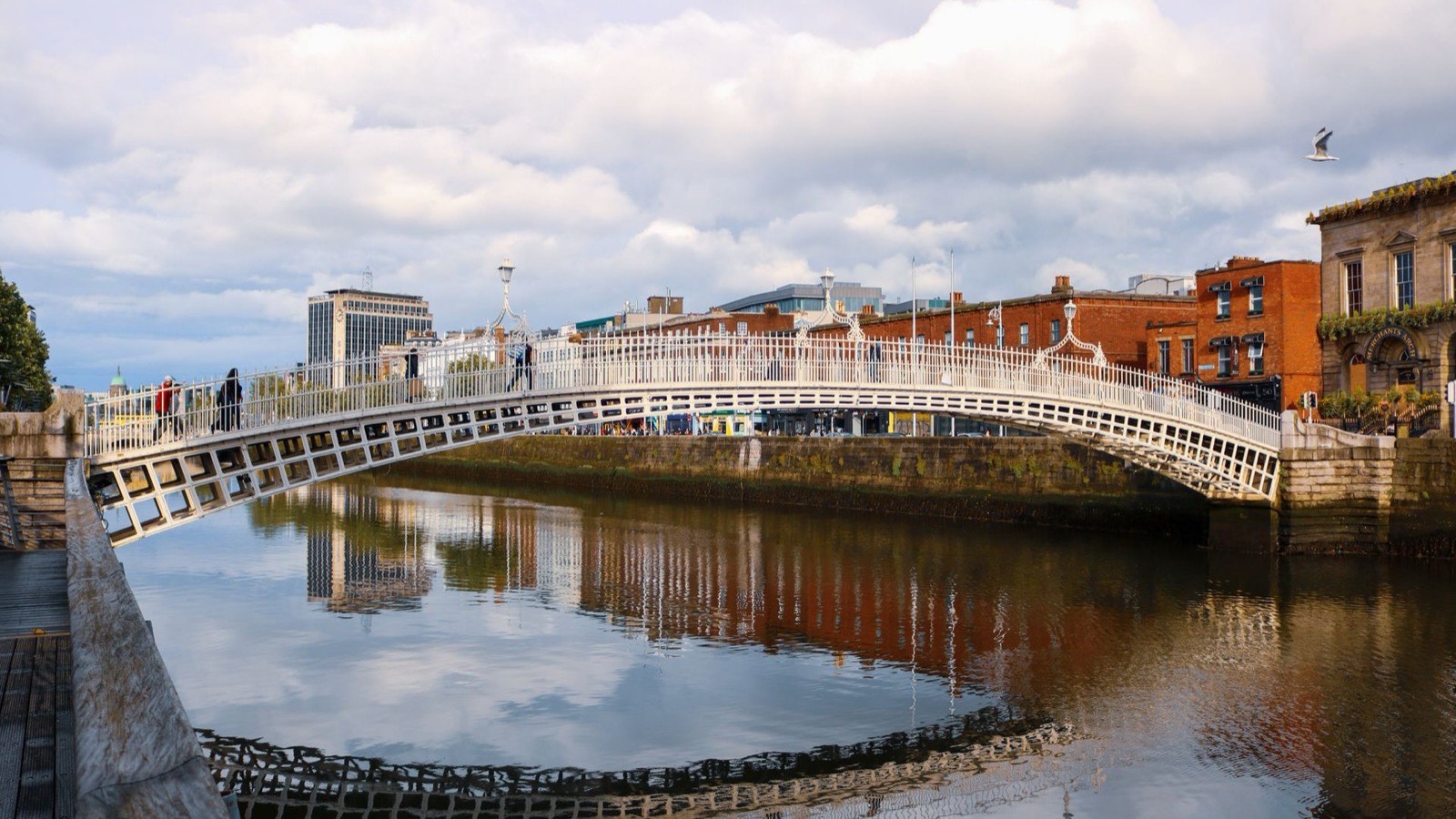 The white iron Ha'penny Bridge over the River Liffey in Dublin, with red-brick buildings behind it